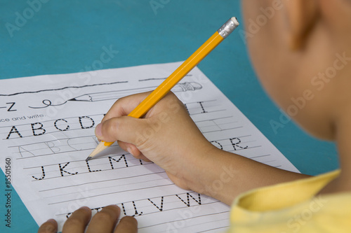 Asian boy traces the letter L with partial blurred view of the face photo