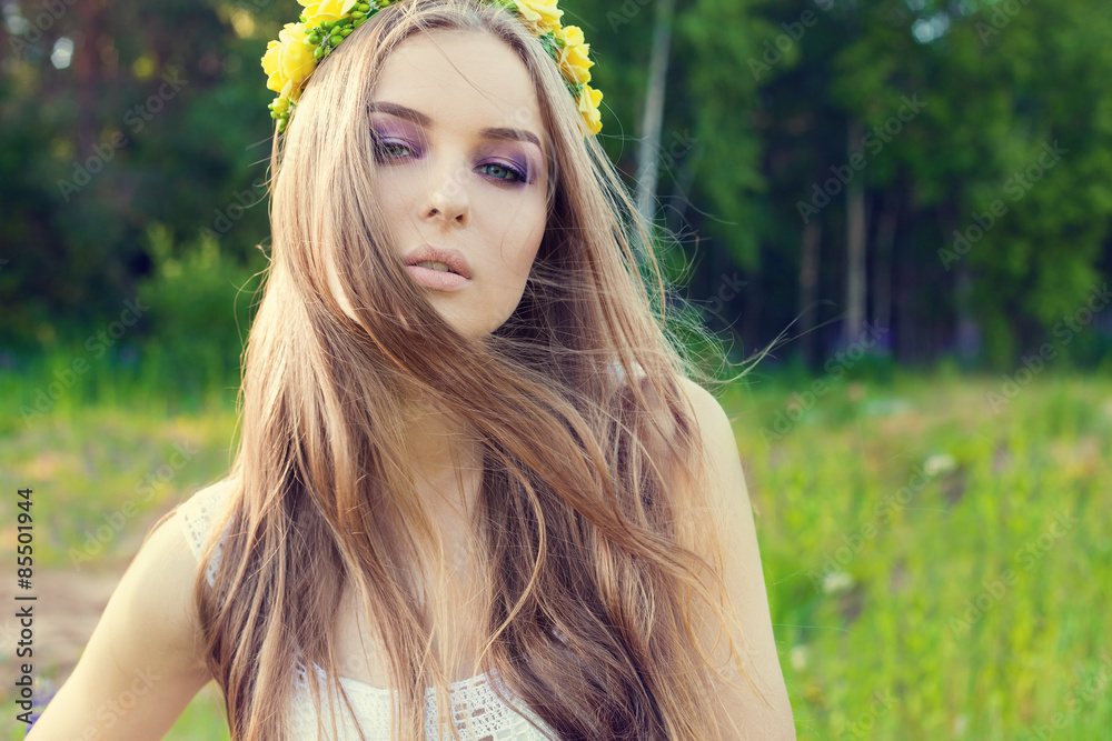 Naklejka premium beautiful sexy sweet girl with long hair and a wreath of yellow roses on his head in the field, the wind blowing her hair