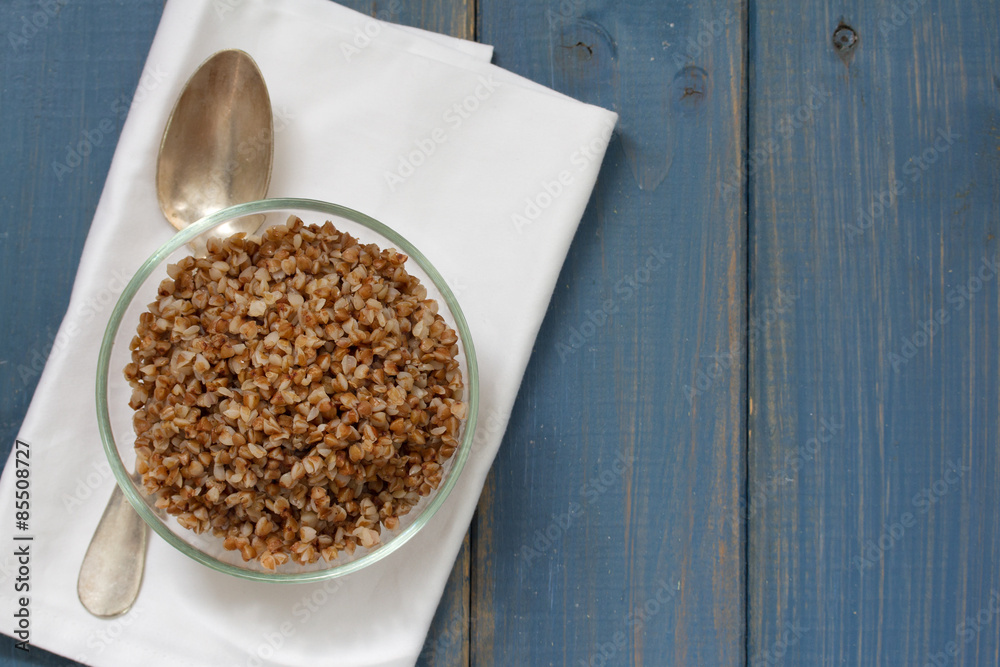 buckwheat in bowl with spoon on blue wooden background buckwheat in bowl with spoon on blue wooden background