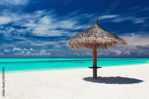 Single tropical beach umbrella on romantic white beach