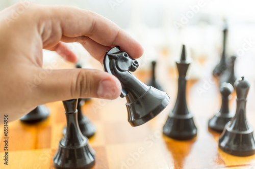 Closeup of male hand holding black horse chess piece