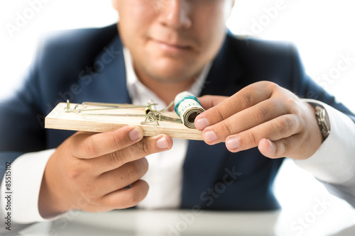Photo closeup photo of man in suit taking money out of mousetrap