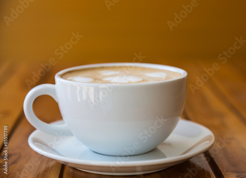 Cup of coffee with heart pattern in a white cup on wood table