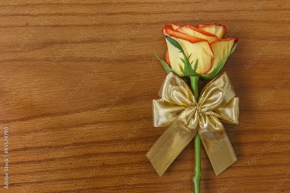 Fototapeta premium Rose and gold decorative bow on the wooden background