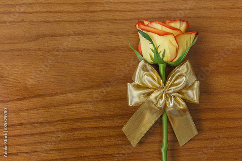 Rose and gold decorative bow on the wooden background
