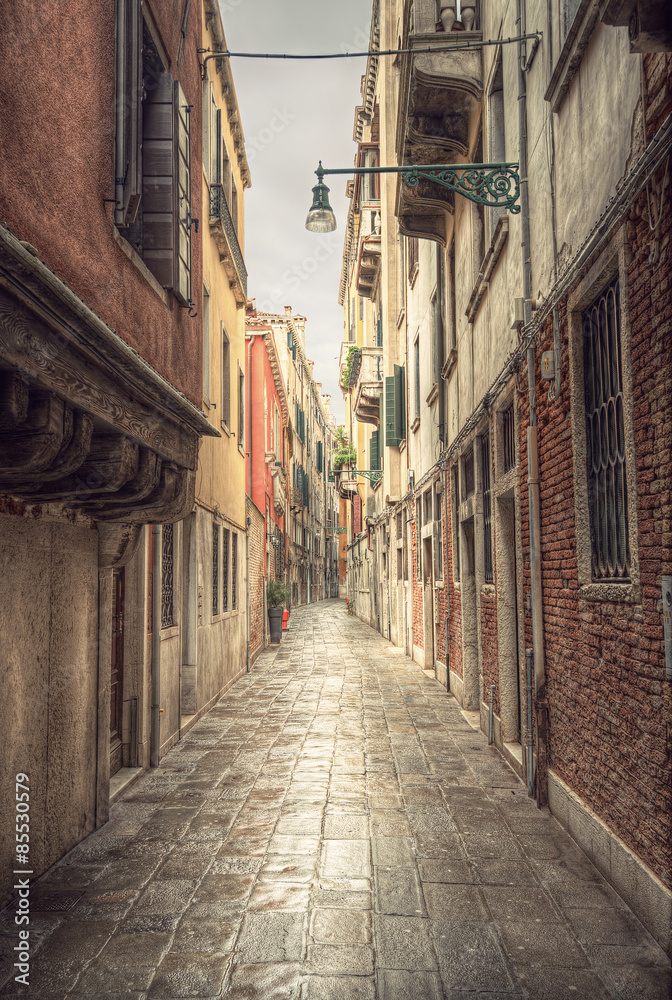 typical narrow alley in street of Venice (Venezia) at a rainy day, vintage style, Italy, Europe