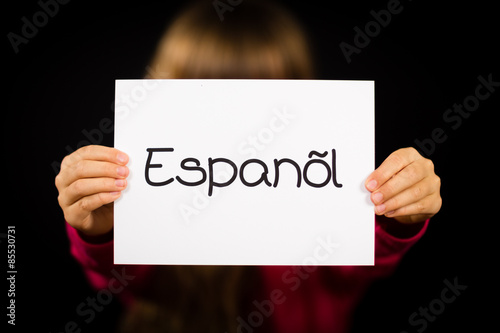 Child holding sign with Spanish word Espanol - Spanish in Englis