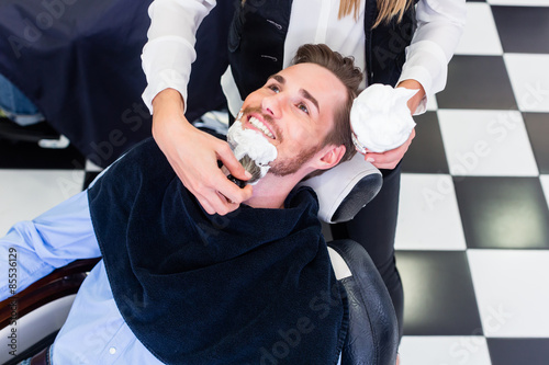 Obraz na plátně Man getting beard shave in barber salon