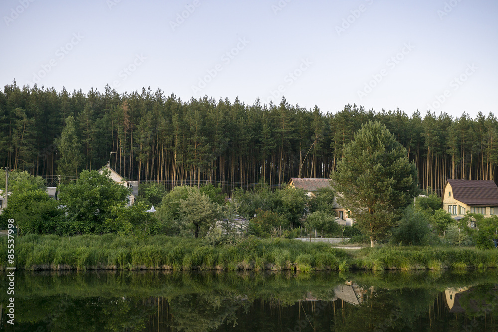 Fototapeta premium River house with reflections and blue sky near the forest
