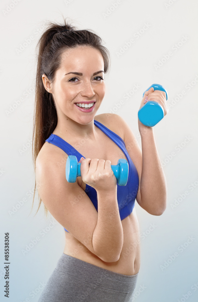 happy athletic woman wearing blue gym bra with dumbbells for workout and toned arm muscles happy athletic woman wearing blue gym bra with dumbbells for workout and toned arm muscles