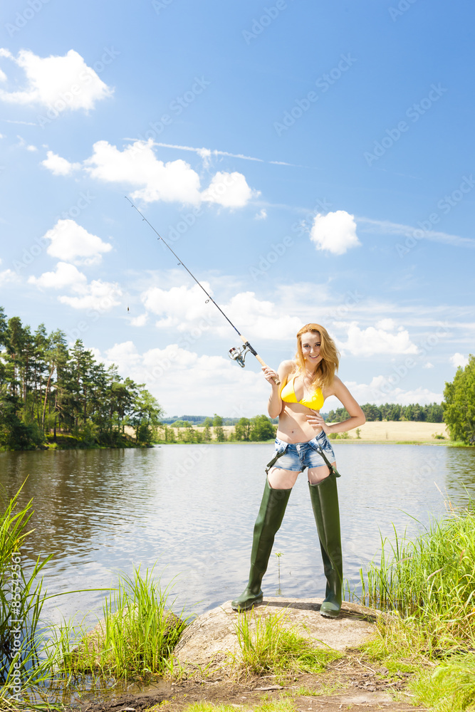 young woman fishing at pond in summer young woman fishing at pond in summer