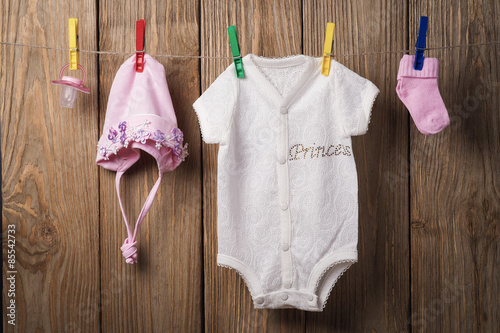 Baby clothing hanging on the clothesline on a wood background photo