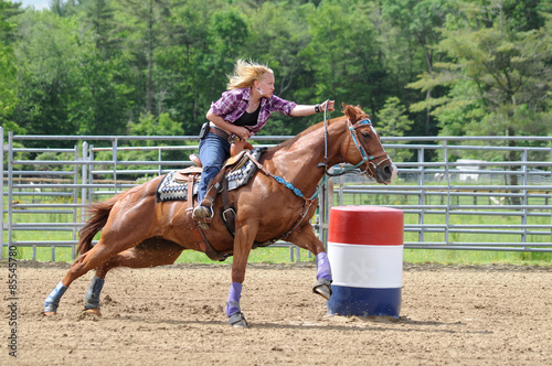 Young adult woman galloping around a turn in a barrel race