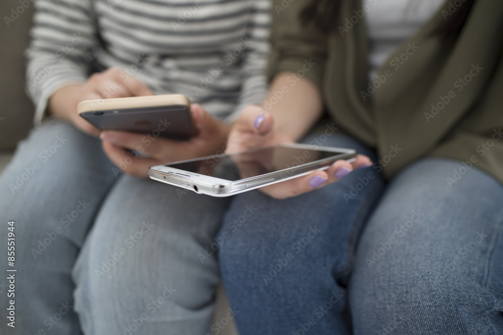 Women looking at smart phone sitting on the sofa Women looking at smart phone sitting on the sofa