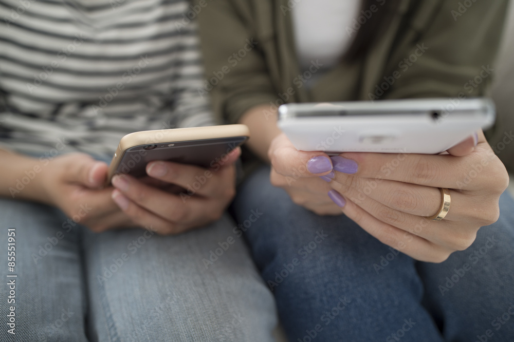 Women looking at smart phone sitting on the sofa Women looking at smart phone sitting on the sofa
