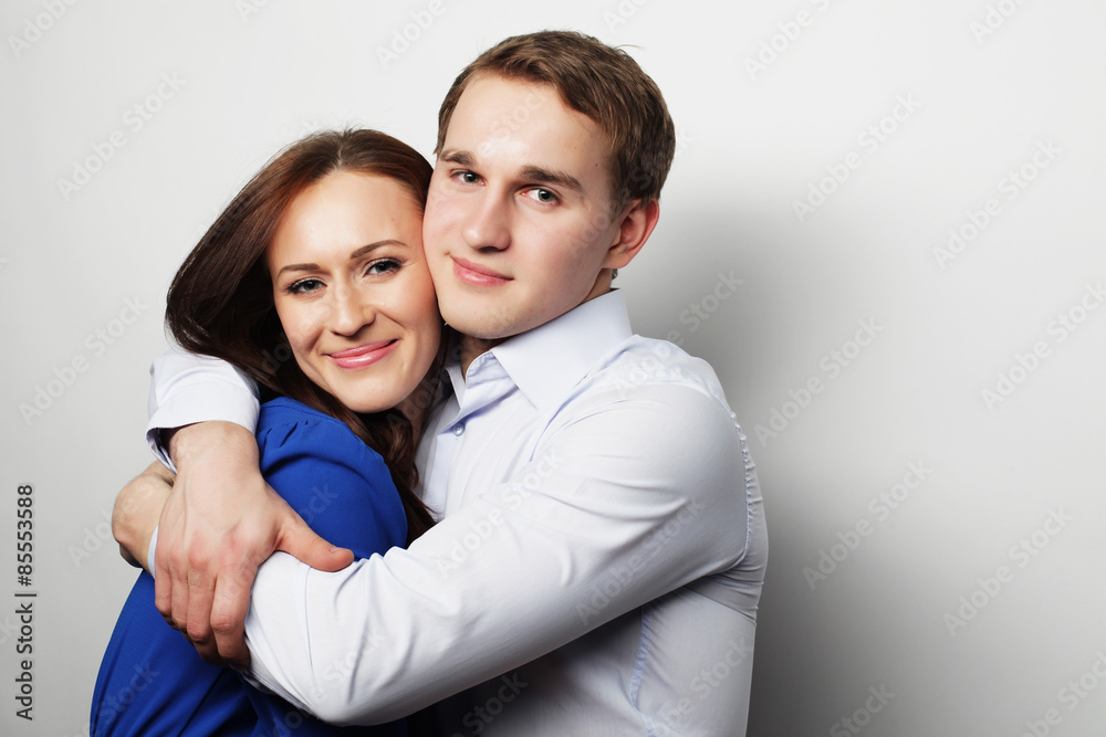 lovely happy couple hugging over grey background. lovely happy couple hugging over grey background.