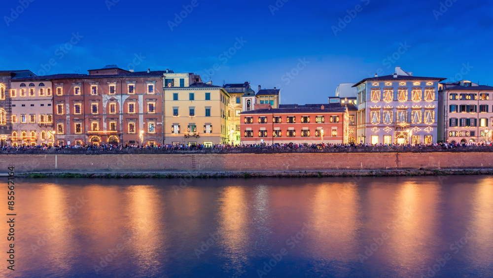 Pisa, Italy. City buildings along river Arno at dusk