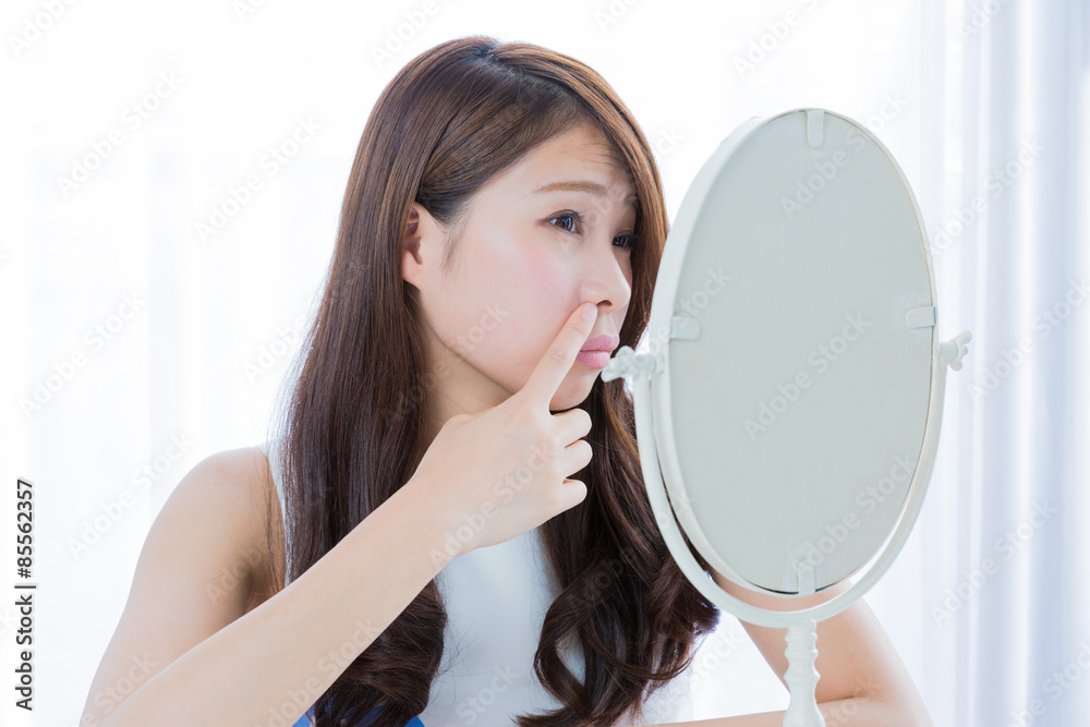 鏡の前で小鼻を指さす女性