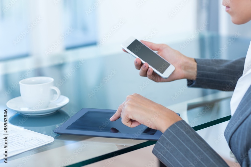 Fototapeta premium Businesswoman using smartphone and tablet