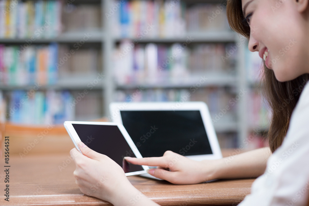 Asian beautiful female student using tablet in library Asian beautiful female student using tablet in library