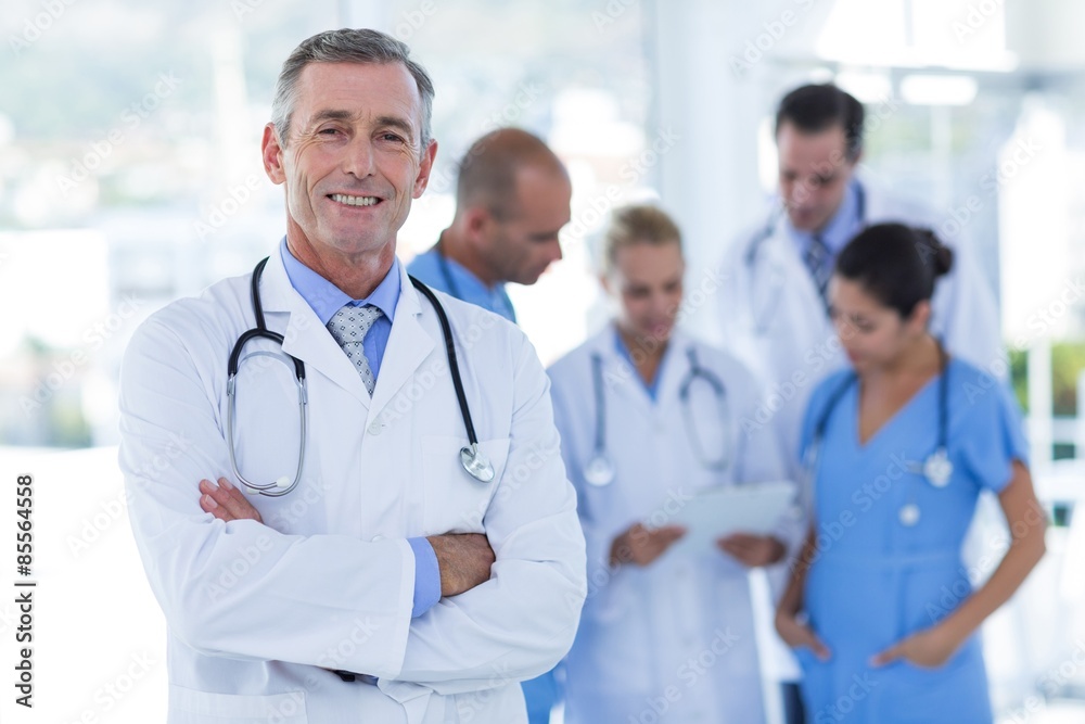 Doctor smiling at camera while his colleague discussing Doctor smiling at camera while his colleague discussing