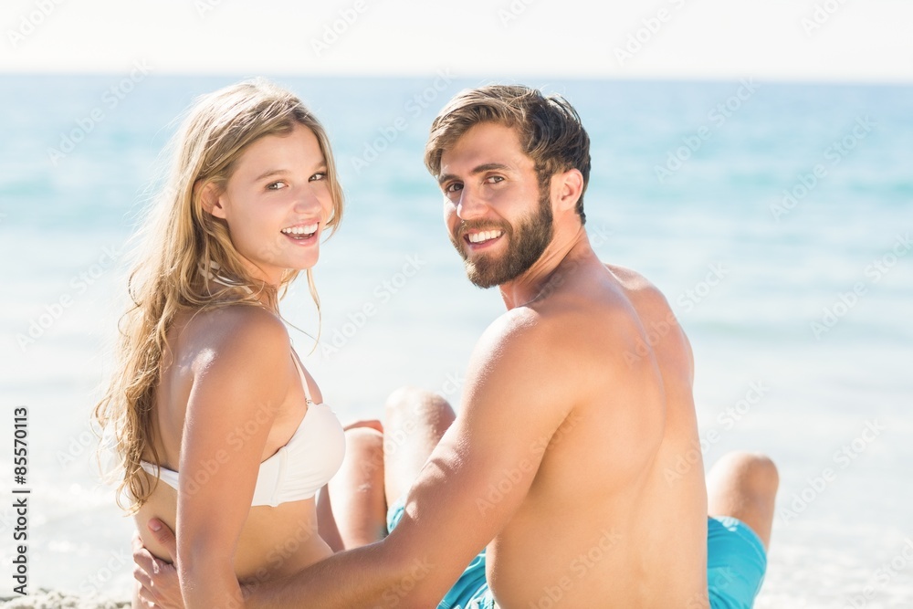 Happy couple relaxing together in the sand Happy couple relaxing together in the sand