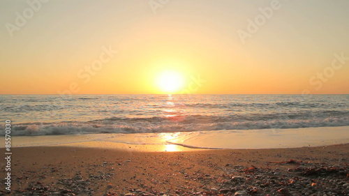 Sunset on the beach - Tranquil idyllic scene of a golden sunset over the sea, waves slowly splashing on the sand