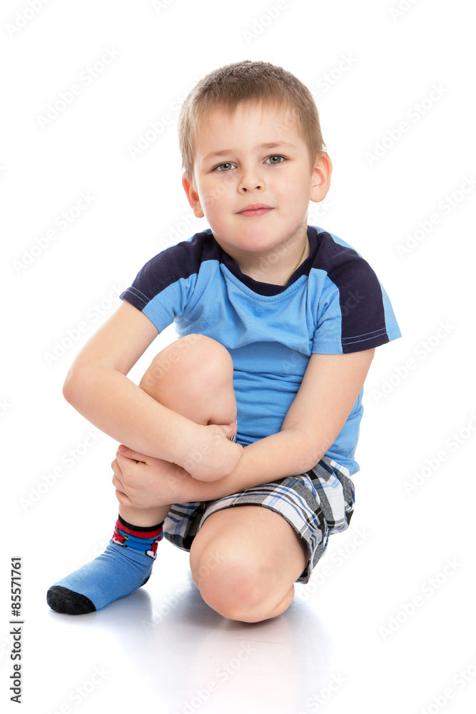 Little boy sitting on the floor clutching her knee Little boy sitting on the floor clutching her knee