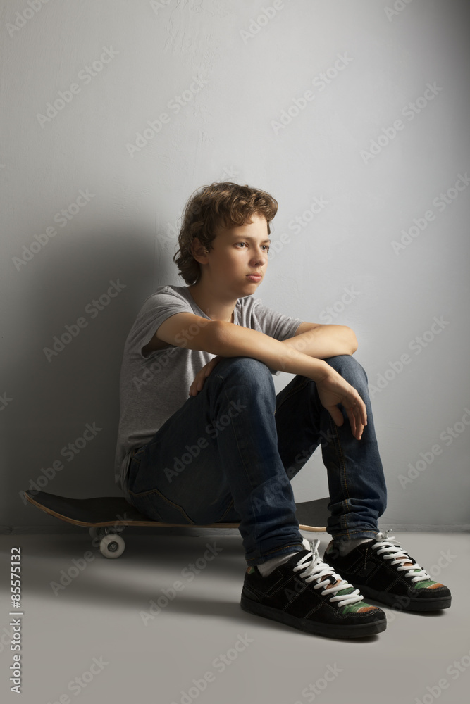 sad teenager sitting on skateboard Stock Photo | Adobe Stock