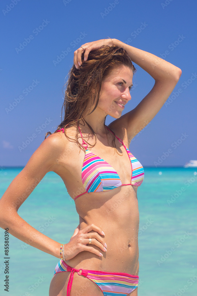 Happy girl in colorful bikini relaxing in sea water on beach