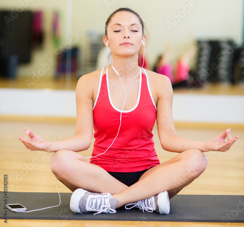 smiling girl with smartphone and earphones in gym