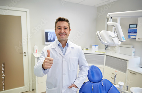 happy male dentist showing thumbs up at clinic