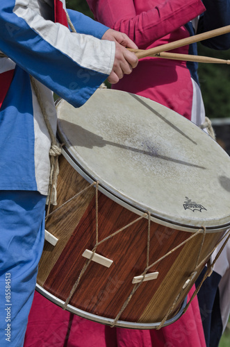 Man plays medieval drum with wooden sticks