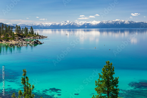 Lake Tahoe calm turquoise waters with view on Sierra Nevada snowy peaks.