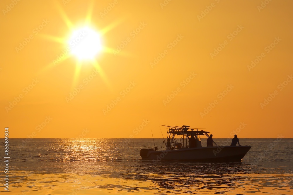 Silhouette of boat with golden sunrise.