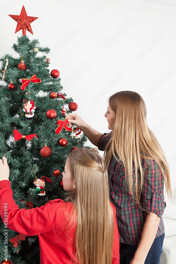 Mother and daughter preparing the christmas tree Mother and daughter preparing the christmas tree