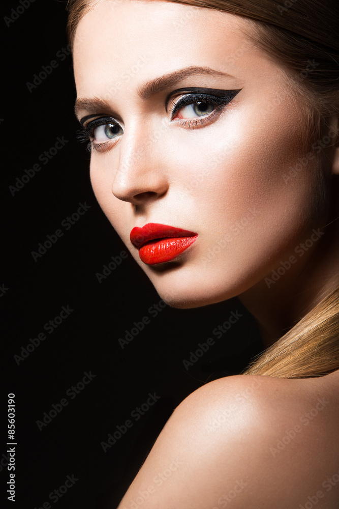 Beautiful girl with unusual black arrows on eyes and red lips and nails. Beauty face. Picture taken in the studio on a black background. Beautiful girl with unusual black arrows on eyes and red lips and nails. Beauty face. Picture taken in the studio on a black background.