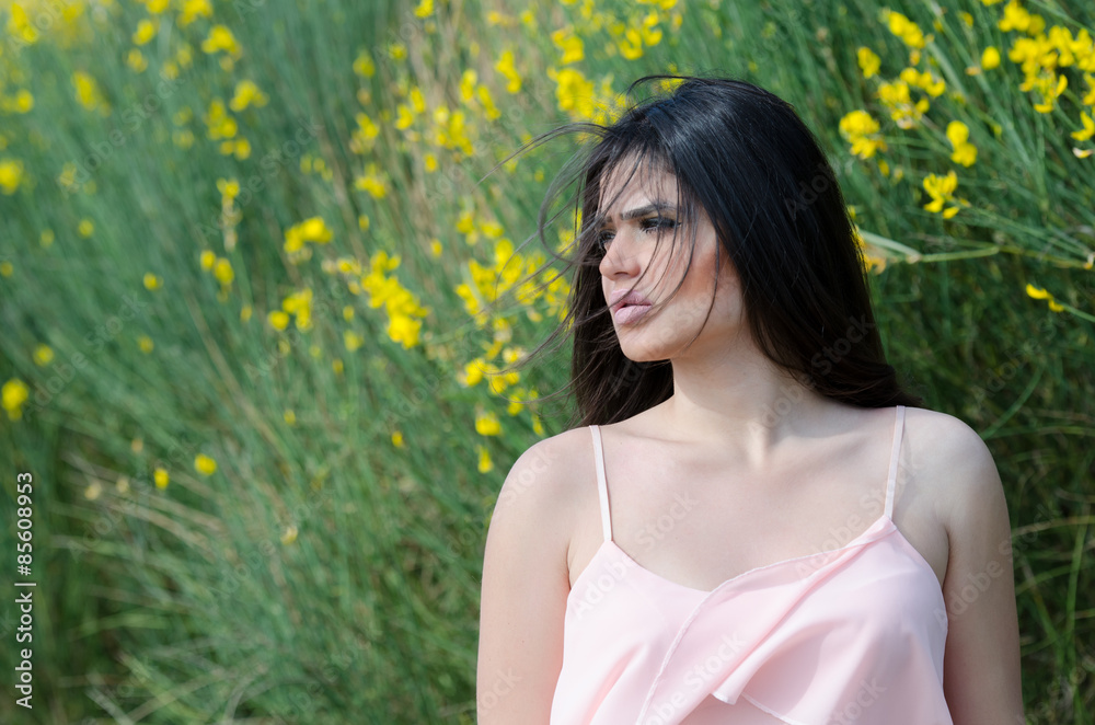 Cute Greek girl standing front of yellow bush