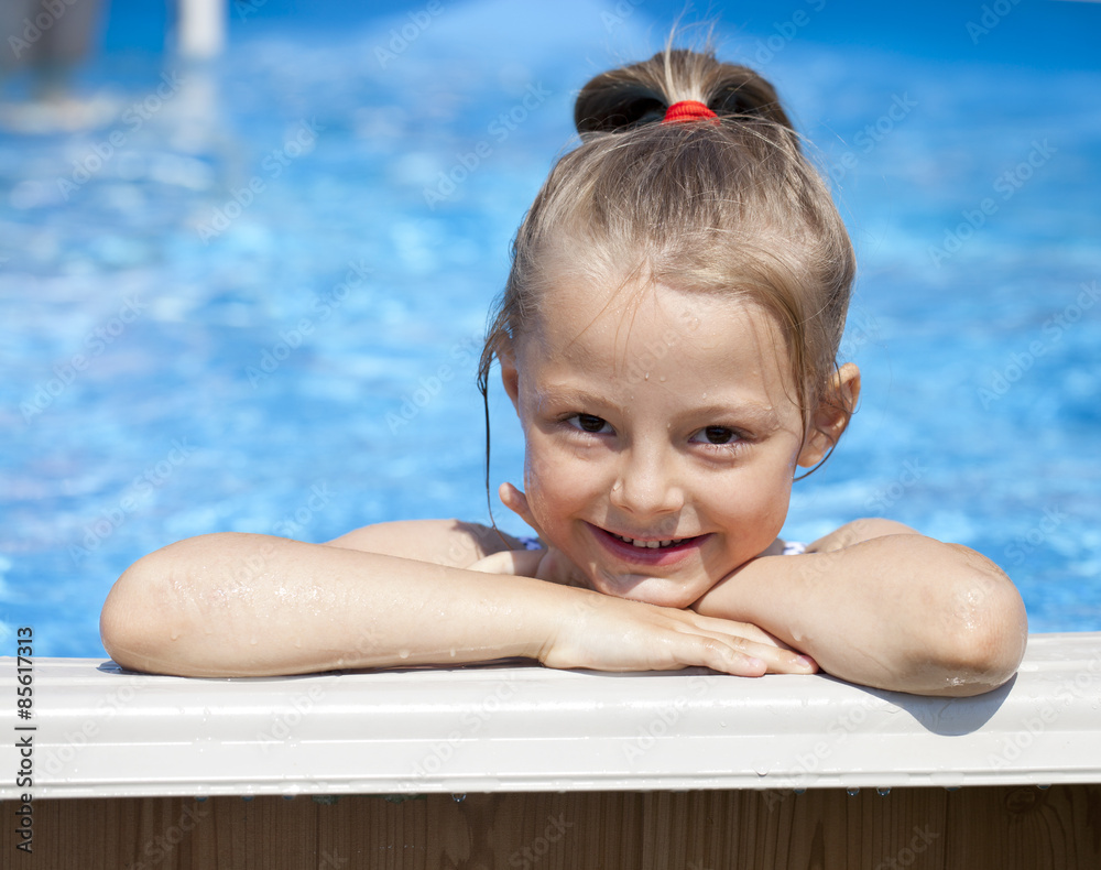 Child girl in blue bikini near swimming pool. Hot Summer Stock Photo
