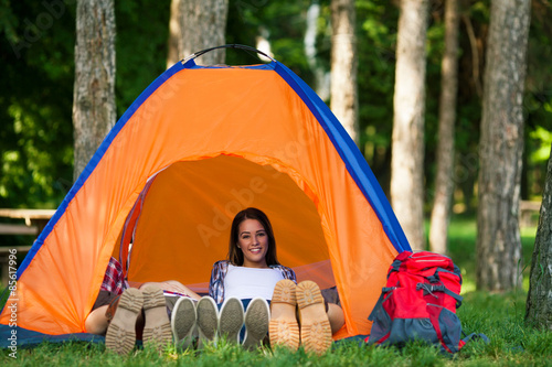 Portrait of young woman relaxing in a tent while camping with friends