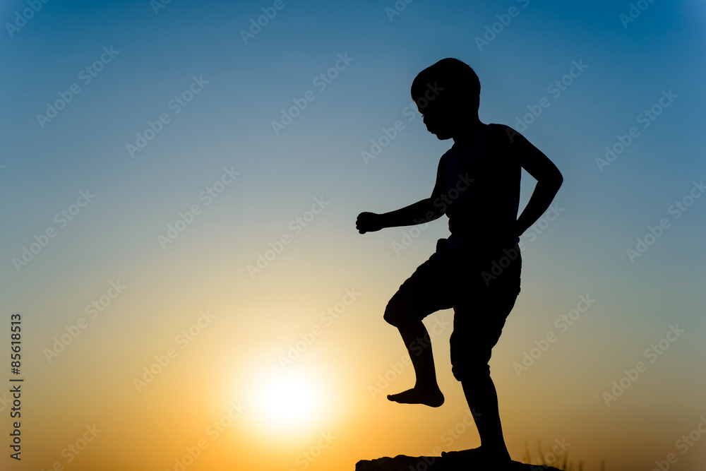 Little boy kicking the setting sun