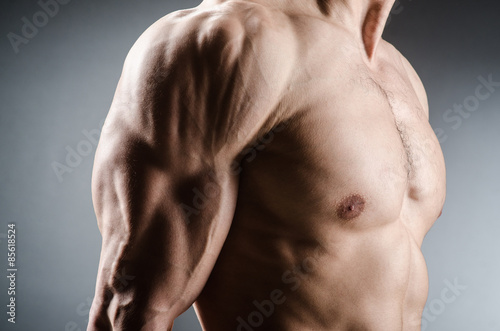 Muscular man posing in dark studio