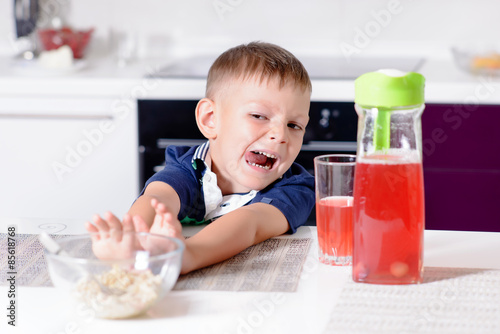 Boy Pushing Away Bowl of Cereal at Breakfast photo