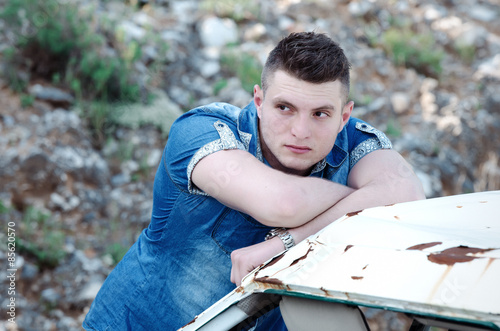 Man in jeans , old damaged car