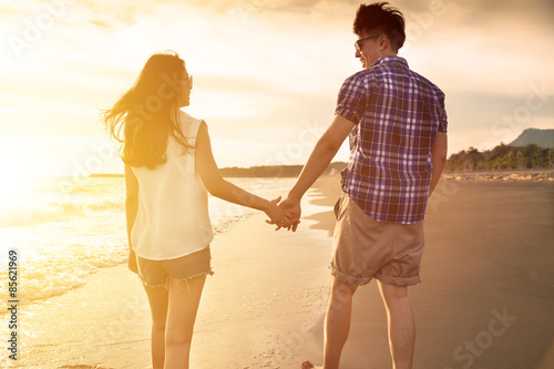young couple enjoying a beach walk at sunset