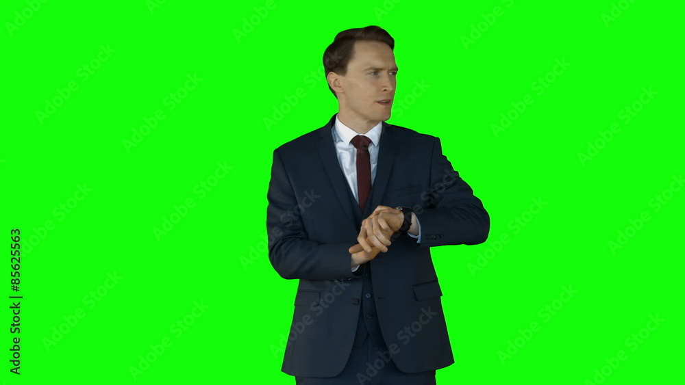 Irritated businessman checking time on green screen Irritated businessman checking time on green screen