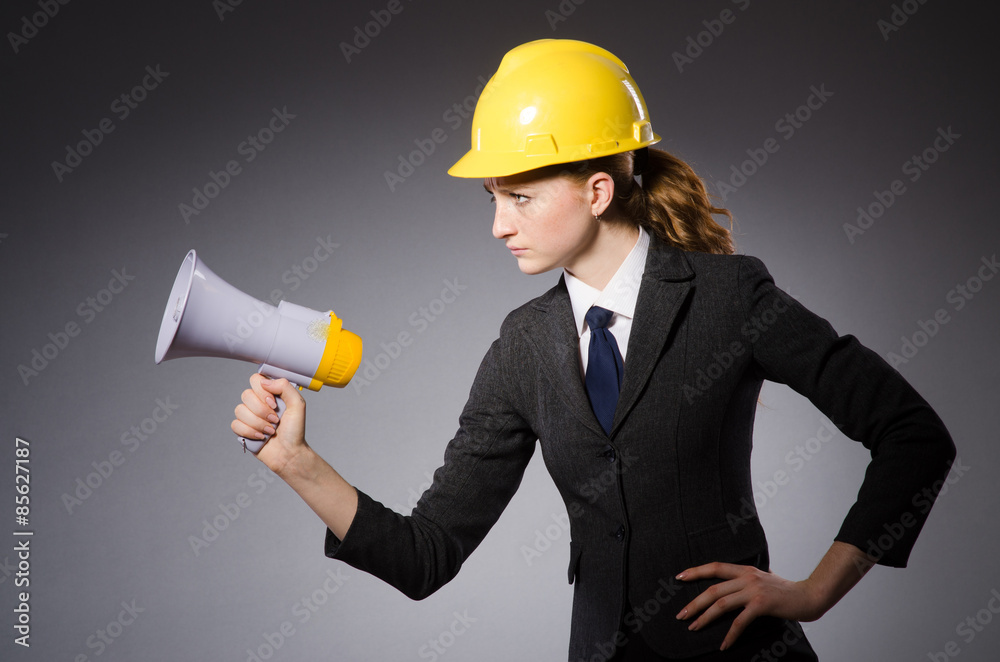 Female engineer with helmet and loudspeaker isolated on gray Female engineer with helmet and loudspeaker isolated on gray