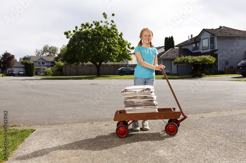 Young girl delivering newspapers with her wagon in her neighbourhood