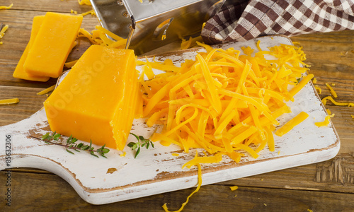 Cheddar Cheese on  a white wooden cutting Board.