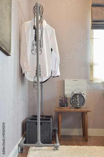white shirts hanging on standing rail and decorative alarm clock © worldwide_stock